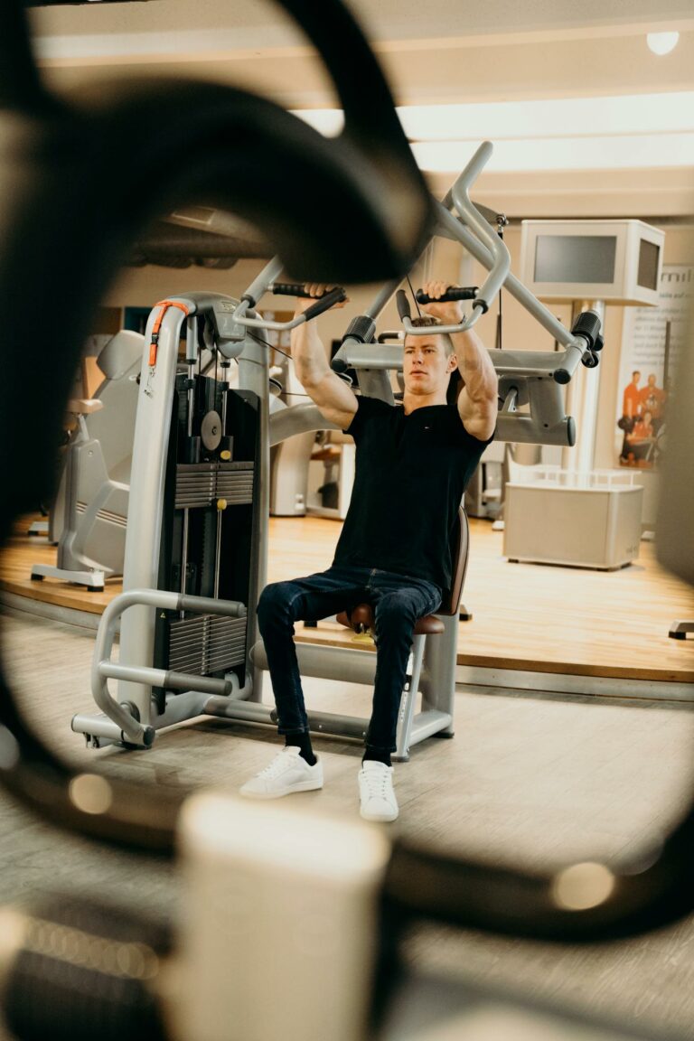 An adult man performing a workout on a fitness machine in a modern indoor gym.